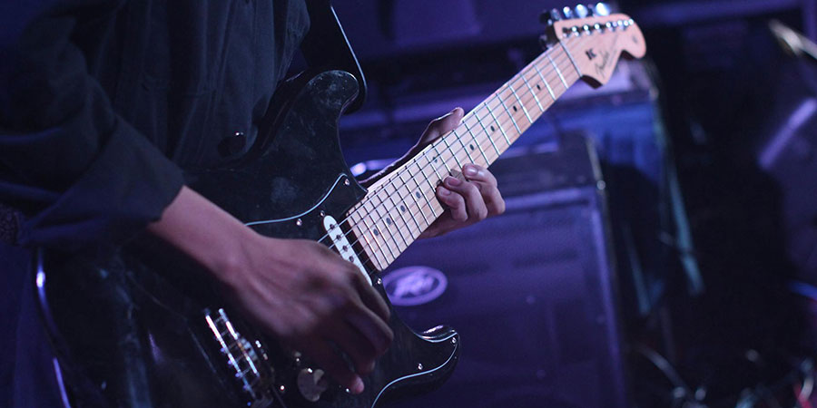 person playing an electric guitar, a Black Fender Stratocaster